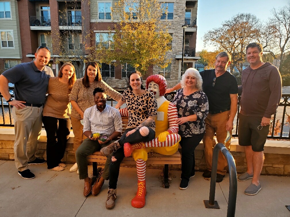 Stark agents and staff pose on a bench next to a Ronald McDonald statue at the Ronald McDonald House